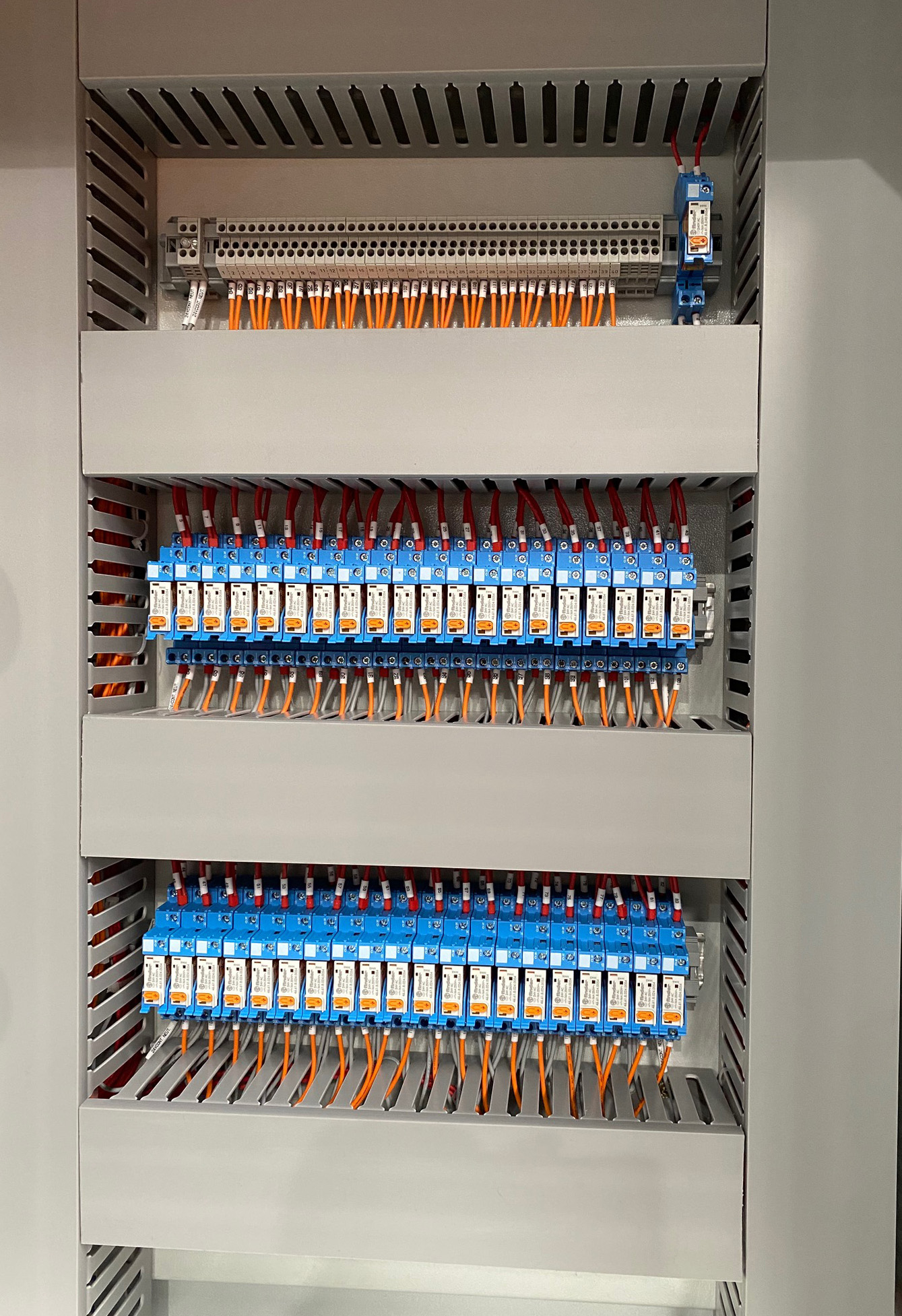 Electrical board densely populated with relays and control modules, featuring organized wiring and terminal blocks