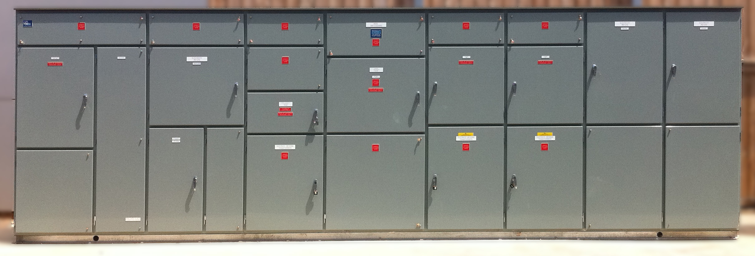 Front view of an industrial electrical switchboard with labeled circuit breakers and safety indicators
